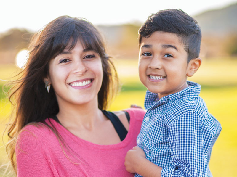 A mother holding her son and smiling.